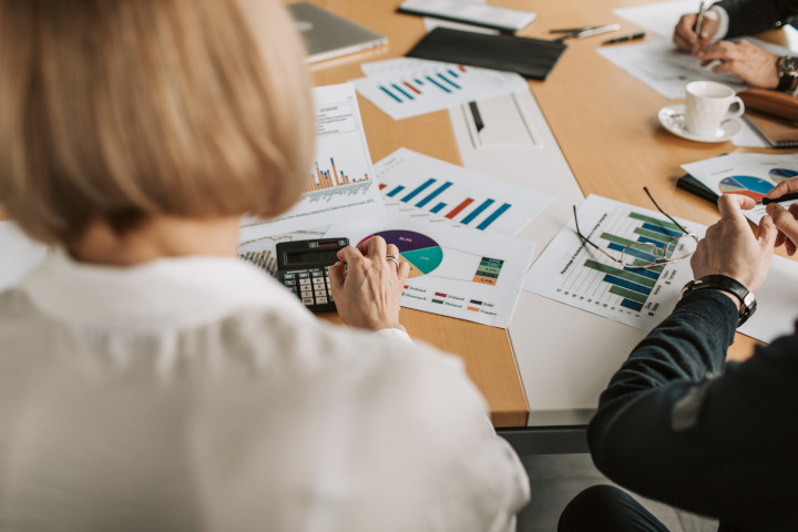 Ausschnitt eines SEO-Teams am Tisch sitzend, auf dem Blätter mit Grafiken liegen